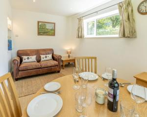 a dining room with a table and a couch at Nursery Cottage in Ewhurst