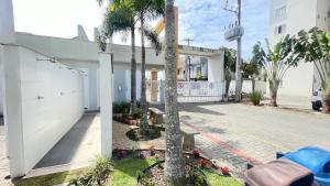 ピサーハスにあるResidencial Angelus Condomínio Clube na Praia de Piçarrasのヤシの木と歩道のある白い建物