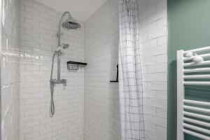 ein Bad mit einer Dusche und weißen Fliesen in der Unterkunft À 400m de la plage, maison renovée pour 6 in Préfailles + 20 Fotos