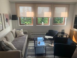 a living room with a couch and chairs and windows at APARTMAN broj 9, SUNČANI BREG RESORT & SPA in Kopaonik