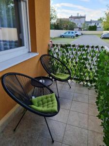 two chairs with green cushions sitting next to a window at Apartman W - self check in in Osijek
