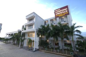 a white building with a sign in front of it at Hotel Sannidhi Emerald in Raigīr