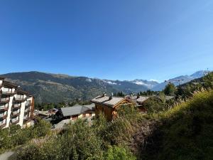 een groep gebouwen op een heuvel met bergen op de achtergrond bij Résidence Grand Bois A310 Clés Blanches in La Tania +5 foto's