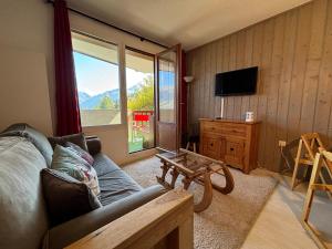 een woonkamer met een bank en een groot raam bij Résidence Grand Bois A310 Clés Blanches in La Tania