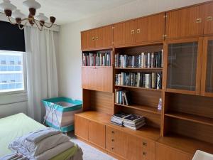 a bedroom with a wooden book shelf with books at Iso kolmio ydinkeskustassa 1-6 hlö Ilm.parkit in Oulu