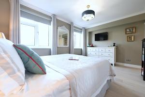 a bedroom with a white bed and a dresser at En-suite luxury large bedroom with parking and two tickets to Kew Gardens in Kew Gardens