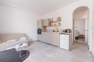 a white living room with a couch and a kitchen at Chic T2 climatisé proche plages in Châteauneuf-lès-Martigues