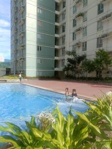 two people swimming in a swimming pool in a building at Belle's Staycation in Cebu City