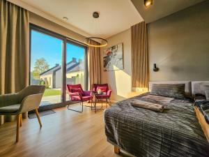 a bedroom with a bed and chairs and a large window at Sand Valley Golf Resort in Pasłęk +264 photos