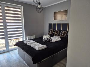 1 dormitorio con cama con sábanas y almohadas negras en ART APARTAMENT MIELNO, en Mielno