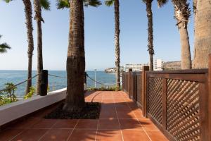 a walkway with palm trees and the ocean at Suite Altamar - by Gestión Vacacional Canarias in Playa del Aguila