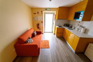 a living room with an orange couch in a kitchen at Casa 14 in Sabugal