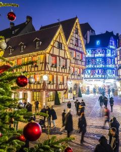 a group of people walking in a town square with christmas lights at Du côté des vignes en Alsace in Turckheim