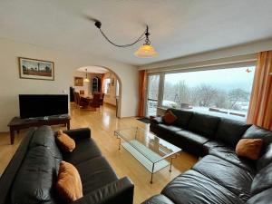 a living room with a black couch and a large window at Ferienhaus Lemmerlinde in Rüthen