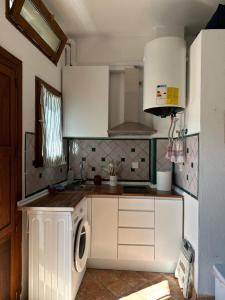 une cuisine avec des armoires blanches et une machine à laver dans l'établissement Casa Cueva Sacromonte BeneVarez Brother Law SL, à Grenade