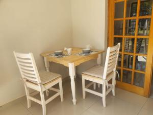 a wooden table and two chairs with bowls on it at Arrival Center BnB in Maseru