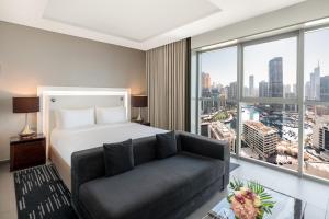 a bedroom with a bed and a couch and a large window at The First Collection Dubai Marina in Dubai