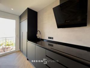 a kitchen with black cabinets and a tv on the wall at Pink Lake view Apartment in Los Altos