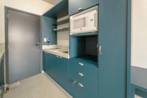 a kitchen with blue cabinets and a microwave at Apartamento Centro Prime CA1404 in Maringá