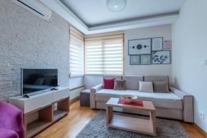 a living room with a couch and a tv at Egoiste Guesthouse Zlatibor Center in Zlatibor