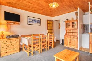 Un comedor con mesa y sillas y un televisor. en Eperon - Les 2 Alpes, en Les Deux Alpes 13 fotos más