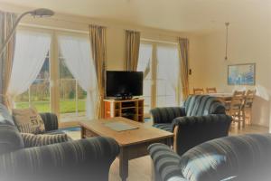 a living room with chairs and a television and a table at Haushälfte Luv und Lee in Tating