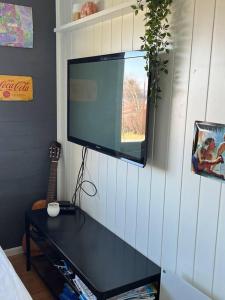 a flat screen tv hanging on a wall with a table at Eget rom og bad med delt kjøkken, 15 minutter fra Trondheim in Malvik