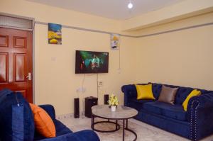 a living room with a blue couch and a table at Ela Stays Nyahururu in Nyahururu