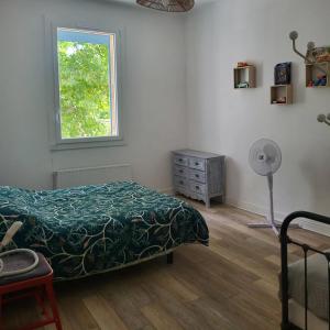 a bedroom with a bed and a window and a fan at Domaine du grand platane in Saint-Paul-Trois-Châteaux