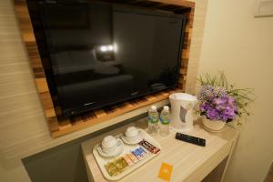 a television on a wall above a table with flowers at Rimba Hotel in Kuala Terengganu