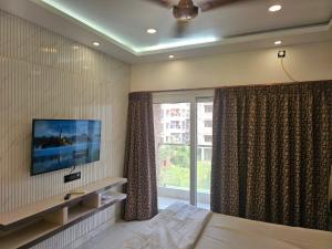 a bedroom with a bed and a tv and a window at LUXE Lagoon in kolkata