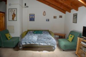 a bedroom with a bed and two green chairs at Case Gran Paradiso Rhemes Saint Georges in Rhemes-Saint-Georges