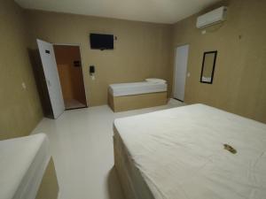 a bedroom with a bed and a toilet and a tv at Karajás Hotel in Quixeramobim +2 photos