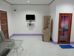 a room with a tv and a chair and a door at Lanta Beautiful beach house in Ko Lanta