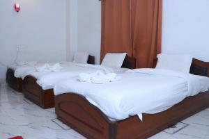 拉明德Hotel Siddhartha in Lumbini的配有白色床单的客房内的三张床