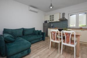 a living room with a green couch and a table and chairs at Relax 1 in Pakoštane