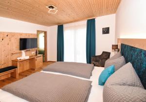a hotel room with two beds and a flat screen tv at Pension Alpenfeeling in Pfronten