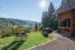 two chairs sitting in the grass next to a cabin at Chalet des Noisetiers - Magnifique vue montagne in Cornimont