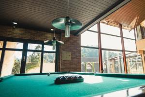 a pool table in a room with windows at Pousada Atalaia Village in Campos do Jordão