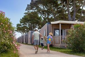 une famille passant devant une rangée de petites maisons dans l'établissement Camping Park Er Lann, à Saint-Pierre-Quiberon