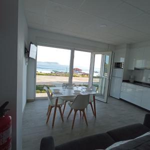 Una cocina y un comedor con mesa y sillas. en Apartamentos NEMIÑA, en A Coruña
