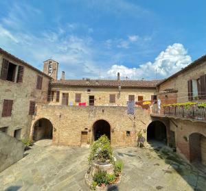 an old stone building with a clock tower in the background at La casina nel convento in Asciano