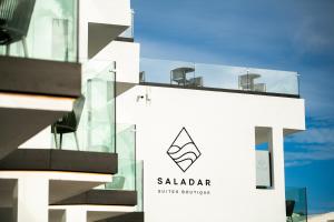 a white building with a glass supreme sign on it at Saladar Suites Boutique in Morro del Jable