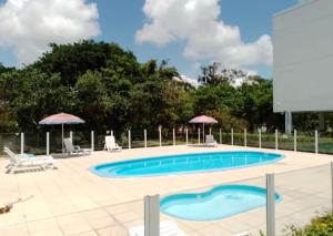 a swimming pool in a yard with chairs and umbrellas at Praia da Cachoeira in Florianópolis