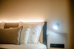 a bed with white pillows and a light on the wall at Saladar Suites Boutique in Morro del Jable