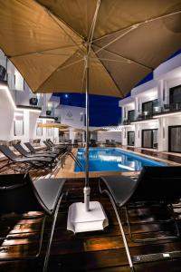a swimming pool with chairs and an umbrella at Saladar Suites Boutique in Morro del Jable