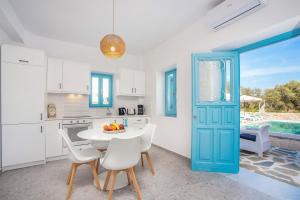 a kitchen with a blue door and a table and chairs at Villa Kalathos Dream White in Kalathos