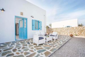 a patio with white chairs and a blue door at Villa Kalathos Dream White in Kalathos