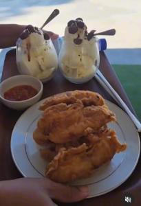 a person holding a plate of food on a table at Kopap Villa in Lalonggasumeto