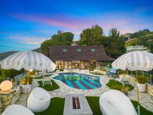 an outdoor swimming pool with chairs and umbrellas at Beverly Tree House in Los Angeles